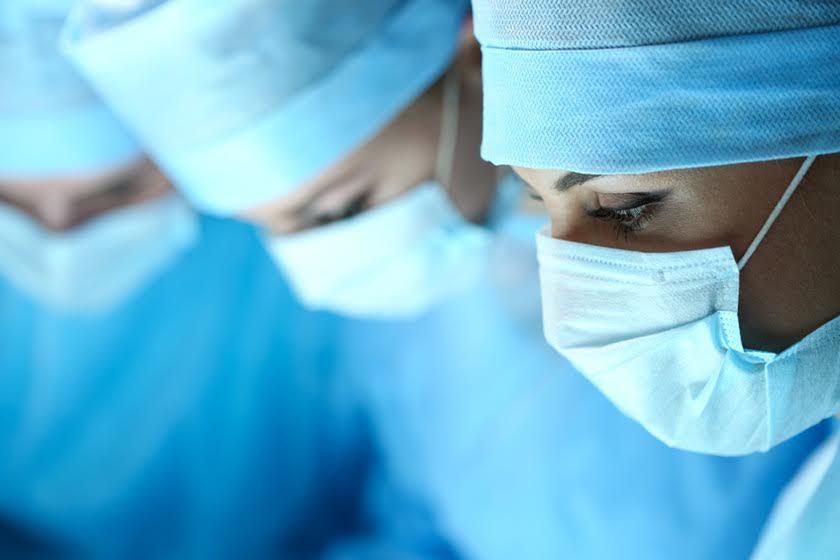 close de médicos com roupa cirúrgica azul e máscaras