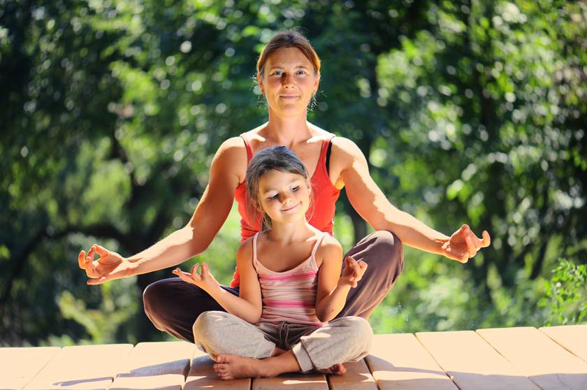 Imagem de mulher e criança sentadas, em posição de meditação - Metrópoles