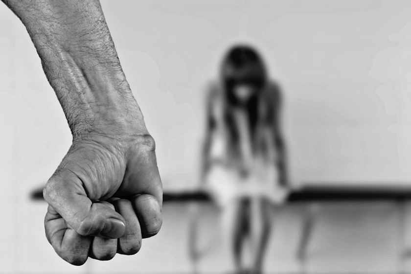 Imagem em preto e branco mostra uma mão fechada em primeiro plano, e, ao fundo, a imagem de uma menina desfocada com a cabeça baixa - Metrópoles