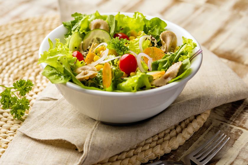 Foto colorida de um recipiente branco com salada dentro