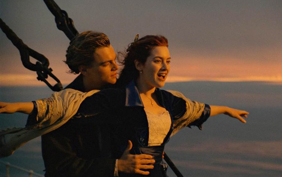 Cena do filme Titanic, com Leonardo DiCaprio e Kate Winslet. Ela é branca, ruiva e está com uma roupa preta e branca. Ele é branco, tem cabelo preto e está utilizando uma roupa preta - Metrópoles