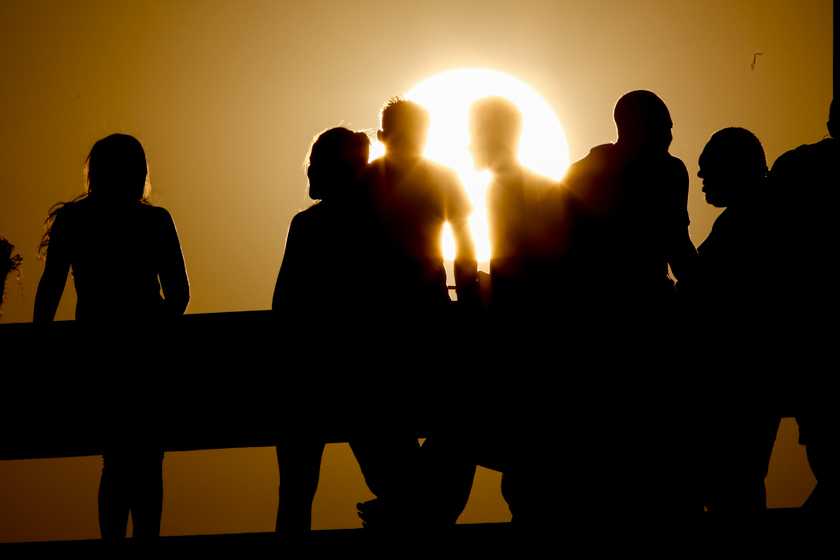 Foto colorida mostra perfil de pessoas com sol ao fundo - Metrópoles