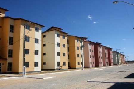 Prédios populares do programa federal "Minha casa, minha vida". Eles são todos similares, com cores variadas e margeiam pista - Metrópoles