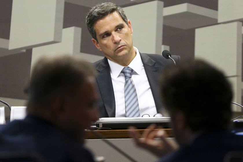 Presidente do Banco Central, Roberto Campos Neto, fala em comissão no Senado Federal durante sua sabatina. No detalhe ele ouve a pergunta de um senador, diante de microfone - Metrópoles