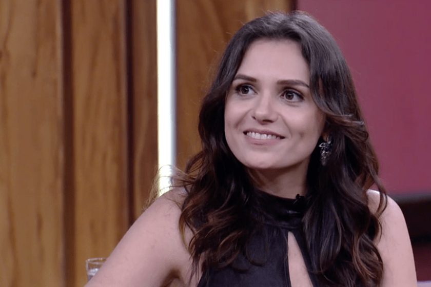 Monica Iozzi sorrindo, com cabelo castanho e look preto - Metrópoles