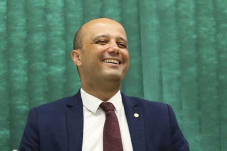 Fotografia colorida de deputado sorrindo para foto