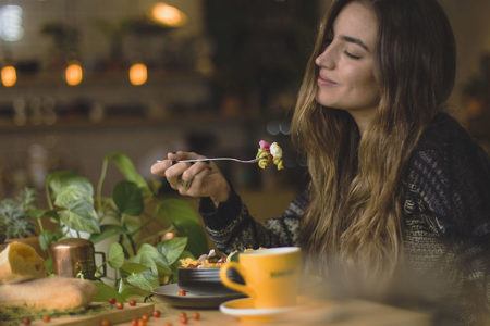 Foto mostra mulher comendo uma pequena porção de comida com uma expressão de saciedade