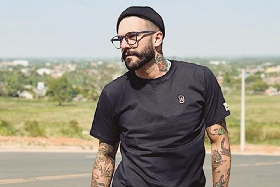 homem de camiseta preta, oculos e touca preta posa olhando para fora da imagem - metrópoles