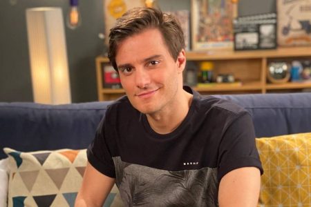 Hugo Bonemer sentado no sofá fazendo carão