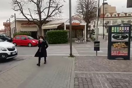 Mulher anda sozinha, com máscara, na rua em cidade italiana