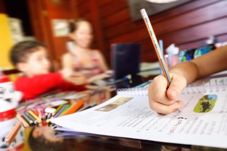 Aluna faz lição de casa junto com a familia