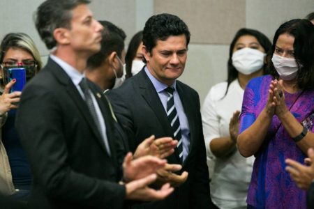 Sergio Moro sorrindo e várias pessoas ao redor, algumas de máscaras
