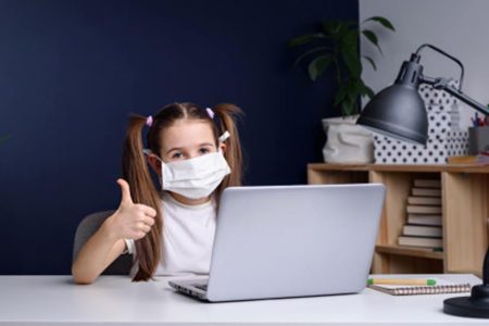 Menina de máscara na frente do computador