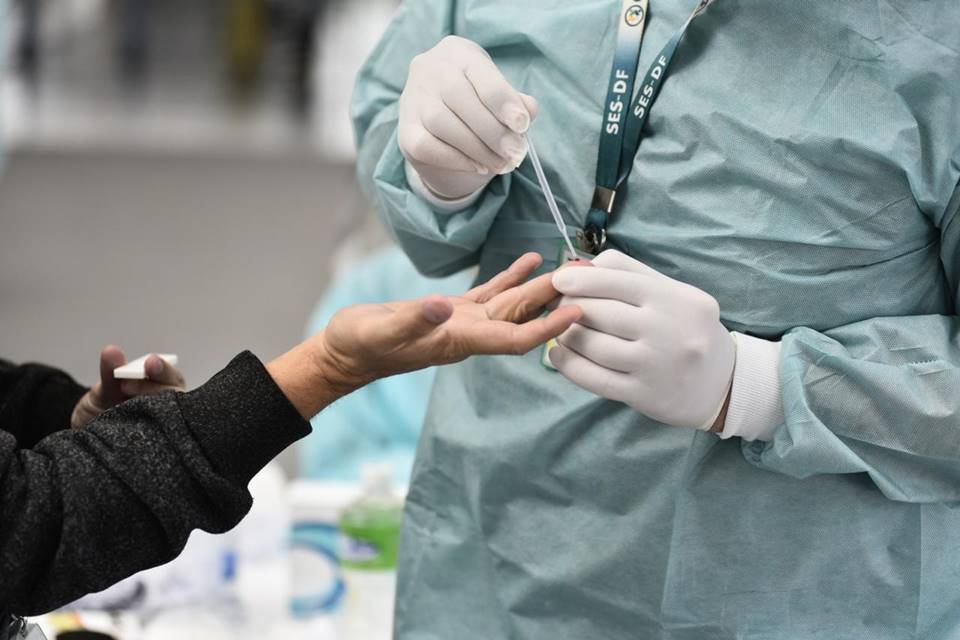 Profissional de saúde colhe material para teste rápido para Covid-19