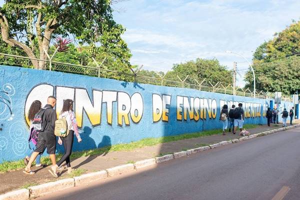Alunos andando em frente a muro de escola azul