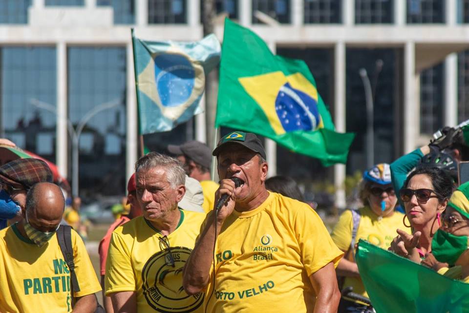 Renan Sena, engenheiro e militante bolsonarista acusado de participar de atos golpistas e terroristas no DF. Na imagem, ele discursa em carro de som, com microfone na mão, cercado de pessoas usando verde e amarelo - Metrópoles