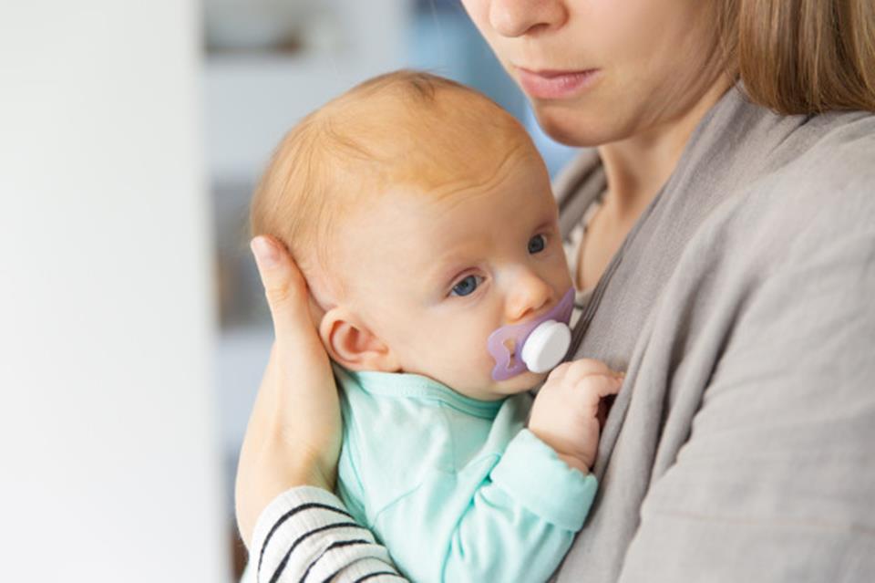 bebê usando chupeta no colo da mãe
