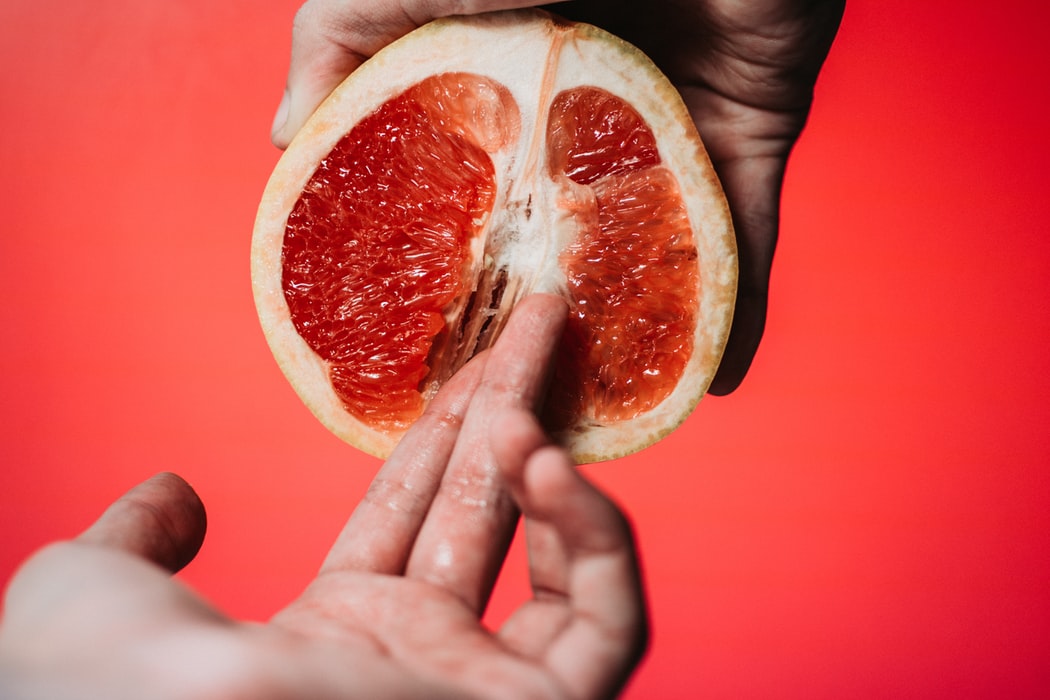 Mão segurando metade de uma laranja