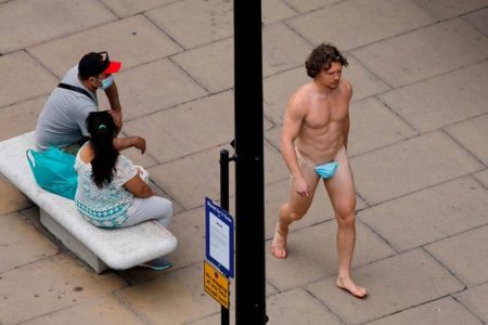 Homem caminha só de máscara na rua