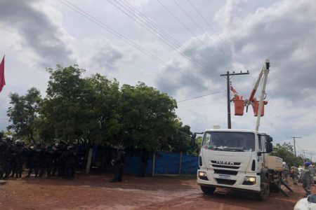 técnico mexendo em poste com forças policiais à esquerda