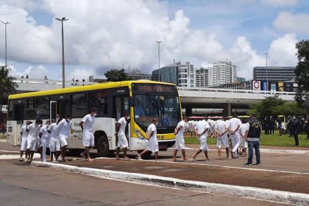 Homens vestidos de branco andam em fila