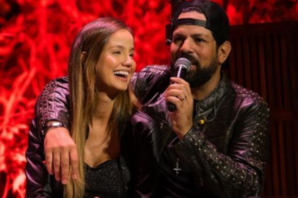 Foto colorida de Biah Rodrigues e Sorocaba, cantor está cantando e usando boné - Metrópoles