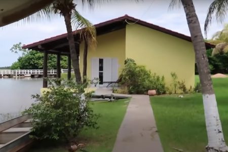 ao fundo, casa amarela e com acesso de concreto que direciona os visitantes até o local. é um dos quartos da fazenda talismã, do cantor leonardo