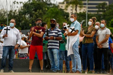 donos e funcionários de bares de goiânia, goiás, em protesto em frente a prefeitura, segurando cruzes e cartazes