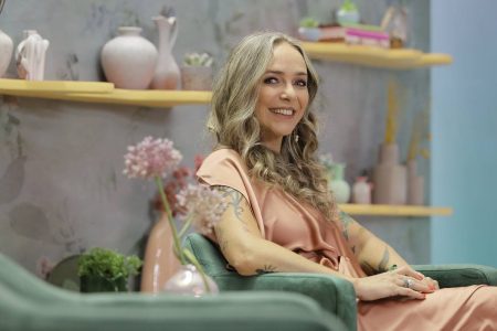 Carole Crema sentada em uma poltrona enquanto sorri