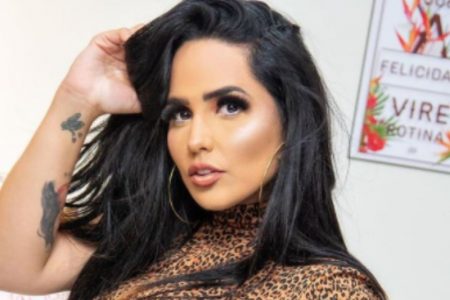 Foto da cantora Perlla. Ela tem cabelos pretos, duas tatuagens no braço direito e usa blusa de oncinha - Metrópoles