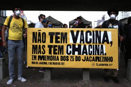 Manifestantes com faixa escrito NÃO TEM VACINA, MAS TEM CHACINA