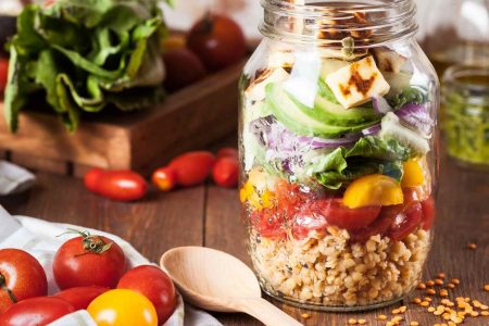 Foto colorida de um pote de vidro que contém uma salada com alimentos ricos em vitamina B