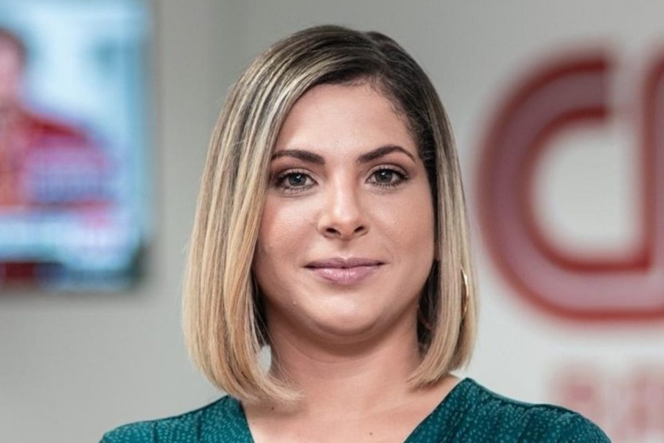 Foto colorida de Daniela Lima. Ela é loira, tem cabelo curto, e está nos estúdios da CNN - Metrópoles