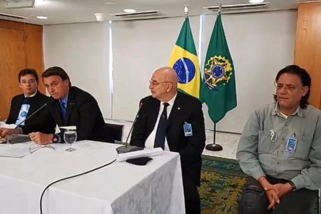 Reunião de Jair Bolsonaro com médicos, na qual ouve ressalvas às vacinas; na mesa, Osmar Terra ao lado de Bolsonaro, com o virologista Paolo Zanoto sentado à direita, na foto, de camisa cinza e cabelos longos