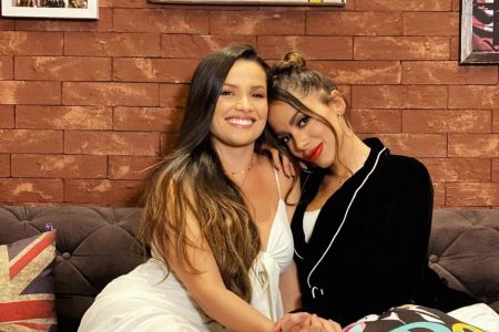 Foto colorida de Juliette e Anitta abraçadas em sofá- Metrópoles