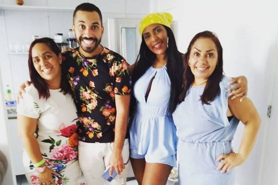 Da esquerda para a direita, posam para a camera e sorriem uma mulher, um homem e outras duas mulheres