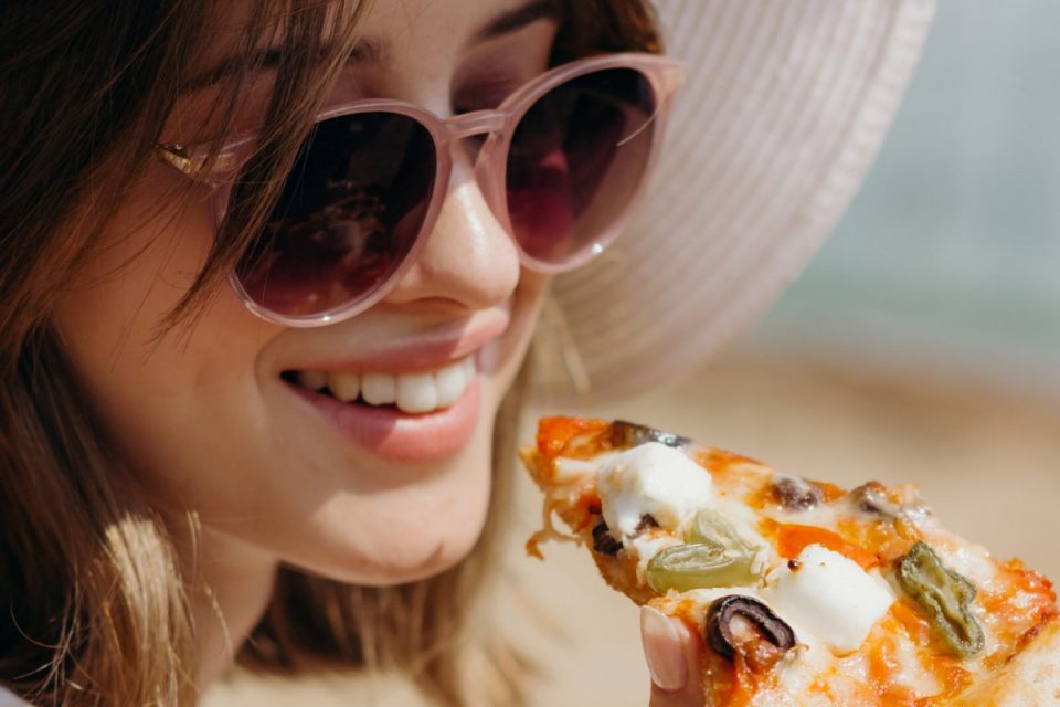 mulher jovem comendo pizza