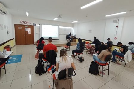 Pessoas sentadas em sala fazendo prova