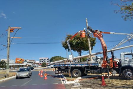 Homem com capacete de segurança, dentro de elevação móvel mexe em fiação elétrica