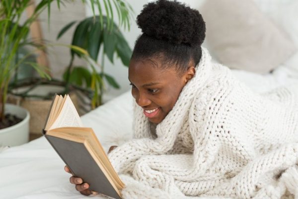 Mulher deitada no sofá lendo um livro