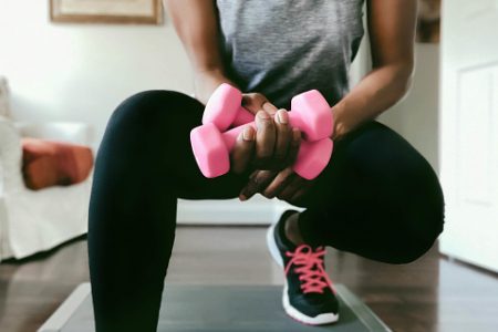Mulher agachada segura pesinhos para malhar