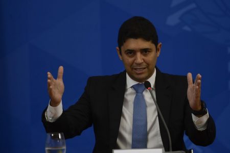 Wagner Rosario, ministro-chefe da Controladoria-geral da União, durante fala no Palácio do Planalto. Ele gesticula com as mãos erguidas e fala diante de microfone e fundo azul - Metrópoles