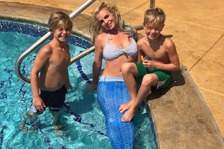 Foto colorida de Britney Spears ao lado dos filhos. Ela está vestida de sereia, e os três estão dentro de piscina - Metrópoles