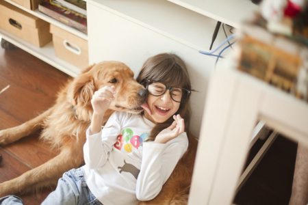 Imagem colorida de um cachorro lambendo criança