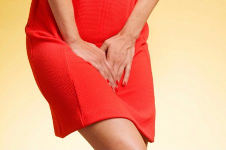 Imagem de mulher com vestido vermelho com as mãos na frente da bexiga - Metrópoles