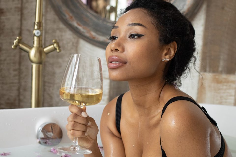 mulher negra banheira taça de vinho