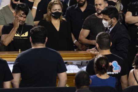 Pessoas de preto em volta de caixão