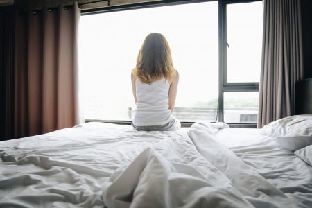 Fotografia colorida de Mulher sentada na cama -Metrópoles