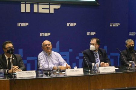 quatro homens dentados atrás de uma mesa. o fundoo é azul com o logotipo do inep