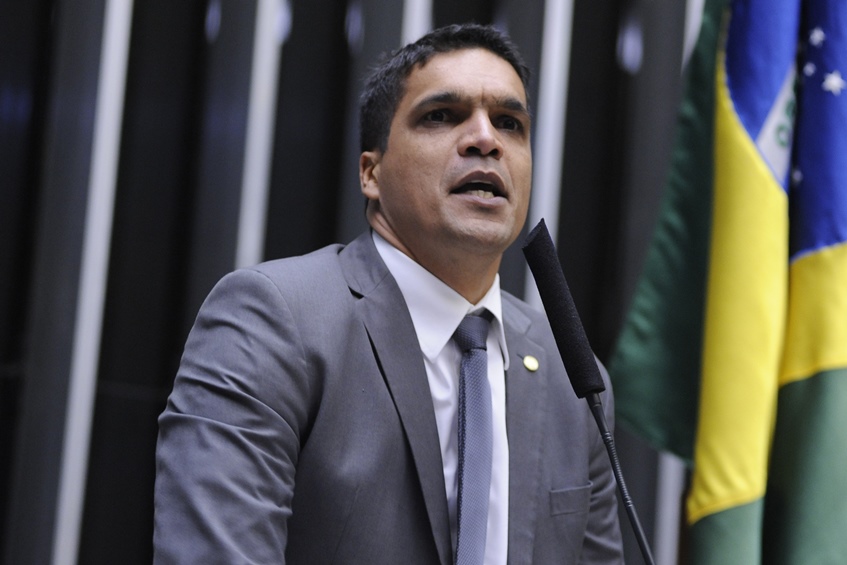 Fotografia colorida de Cabo Daciolo. Na foto, ele aparece falando em púlpito do Congresso Nacional. Ao fundo, desfocada, a bandeira do Brasil